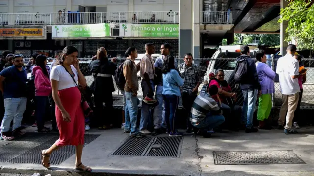 Una fila de gente para comprar bienes básicos.