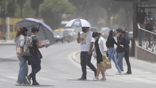 Personas con paraguas caminando por las calles de Puebla.