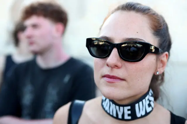 Žena sa ogrlicom na kojoj piše Kanje Vest pred koncert u Tirani 11. jula 2026.