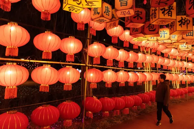 Человек идет мимо горящих красных фонариков