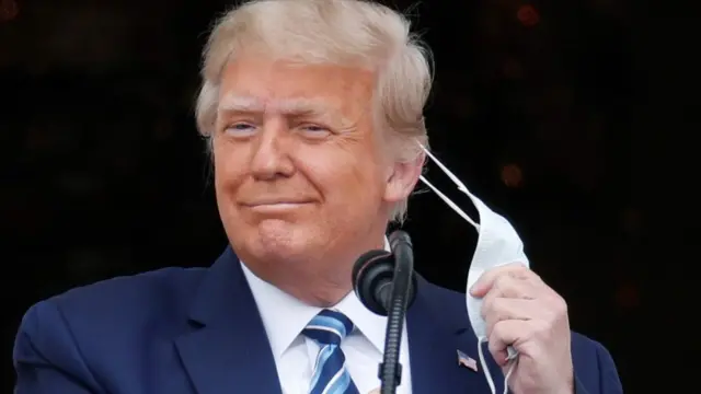 U.S. President Donald Trump takes off his face mask as he comes out on a White House balcony to speak to supporters gathered on the South Lawn for a campaign rally that the White House is calling a "peaceful protest" in Washington, U.S., October 10, 2020.