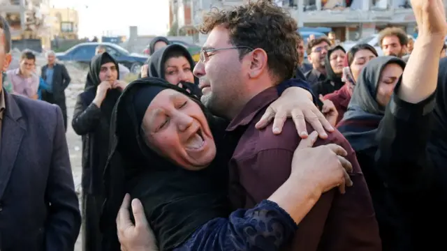 Una mujer y un hombre lloran junto a viviendas afectadas por el terremoto.
