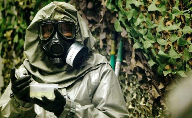 An instructor at the Fort Leonard Wood Chemical School, who is designated as an agent handler, carries the VX nerve agent to contaminate a jeep in one of the eight chambers used for training chemical defense 18 April 2003 at Fort Leonard Wood, Missouri.