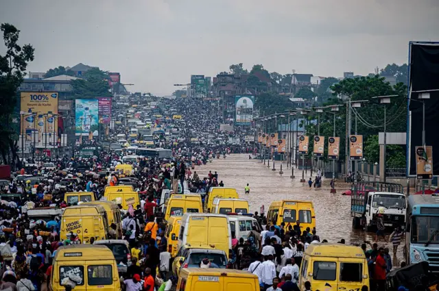 Des habitants pataugent dans des eaux troubles suite à de fortes pluies dans le district de Ndjili à Kinshasa le 6 avril 2025.