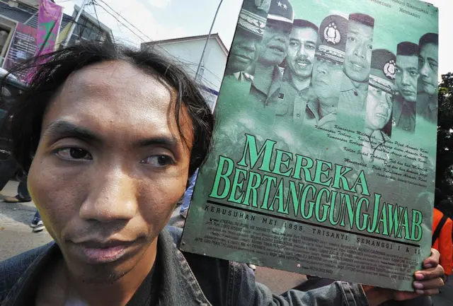 Seorang aktivis, memegang poster dengan gambar-gambar para jenderal yang terlibat dalam memadamkan protes selama kerusuhan 1998, mengambil bagian dalam protes di luar kantor jaksa agung di Jakarta pada 12 Mei 2008.