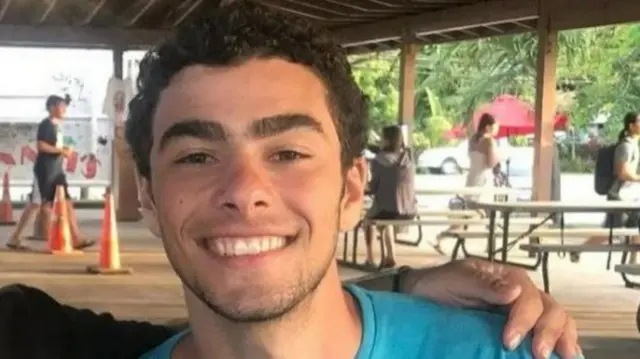 Mangione sorrindo para foto, com alguém ao seu lado o abraçando