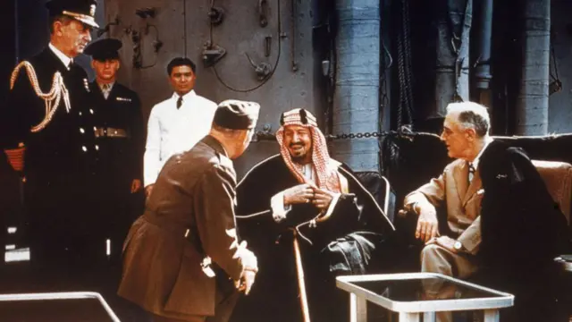 O então presidente americano Franklin Delano Roosevelt reunido com o rei Ibn Saud, da Arábia Saudita, o chefe do Estado-Maior americano William D. Leahy (de joelhos) e o coronel William A. Eddy, a bordo do navio USS Quincy no canal de Suez, Egito, no dia 14 de fevereiro de 1945.
