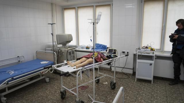 Евгений Малолетка фотографирует тело девочки, погибшей в результате обстрела жилого квартала, в городской больнице Мариуполя, 27 февраля 2022 года (фотография Мстислава Чернова)