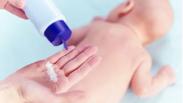 madre a punto de aplicar talco a su bebé.