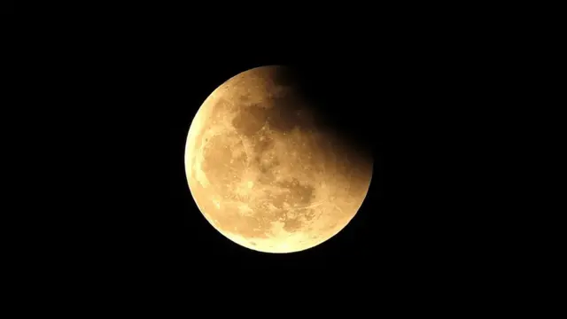 A partial eclipse is seen before a rare super blood moon is revealed during a total lunar eclipse in Manila, Philippines, 26 May 2021.
