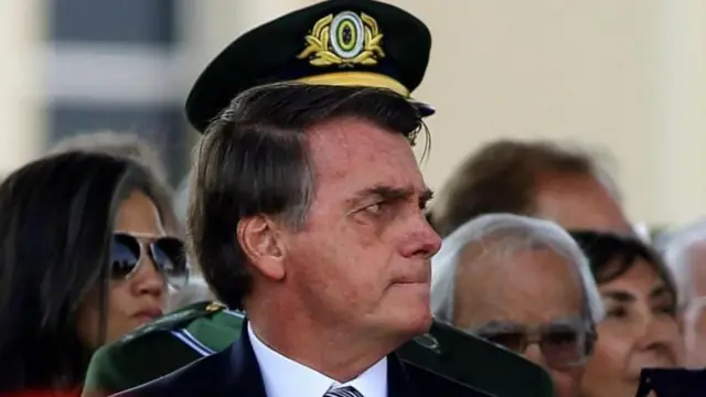 FotoJair Bolsonaro com chapéu militar ao fundo