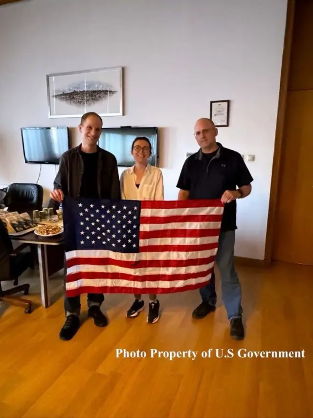 Tutsak takasında serbest bırakılan ABD vatandaşları Evan Gershkovich, Alsu Kurmasheva ve Paul Whelan'ın Amerikan bayrağı ile çekildiği fotoğraf.