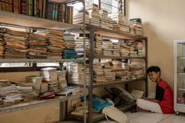 Seorang santri membaca Alquran di depan rak yang penuh dengan tumpukan buku, di Pondok Pesantren Hamalatul Quran Al-Falakiyah selama bulan suci Ramadan, 4 April 2023 di Bogor, Jawa Barat, Indonesia.