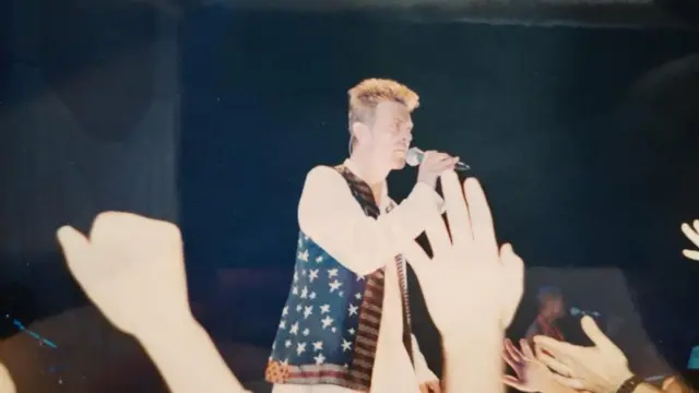 Dejvid Bouvi drži mikrofon u prsluku sa belim zvezdama