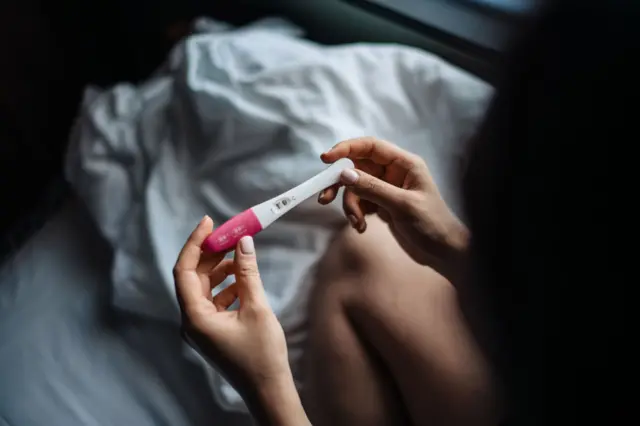 Жінка тримає в руках позитивний тест на вагітність 