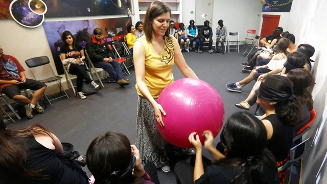 Profesora mostrando una pelota de pilates que representa al Sol