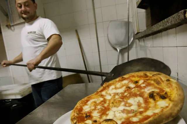 Cocinero sacando pizza