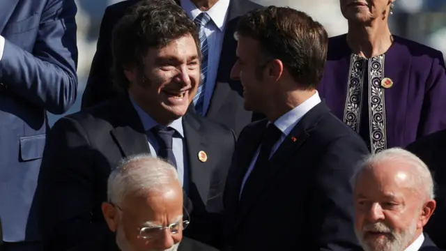 Milei cumprimenta o presidente da França Emmanuel Macron durante encontro do G20. Ambos estão sorrindo. 