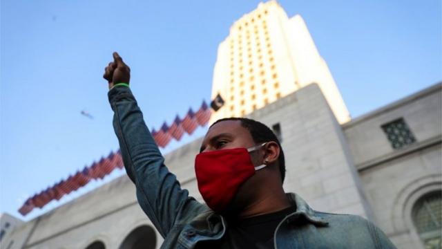 當示威者聚集在洛杉磯市政廳前時，一名男子舉起拳頭
