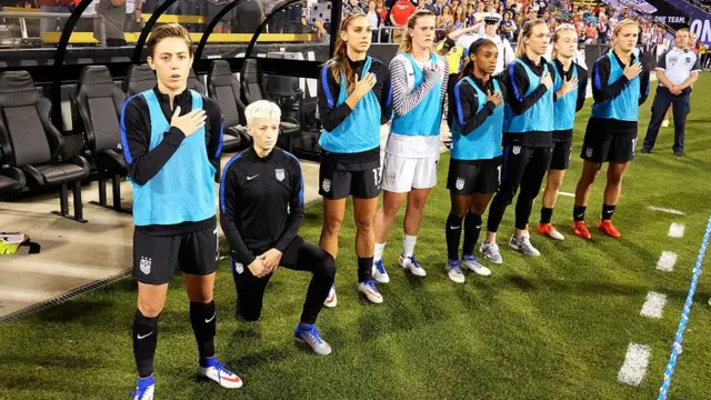 Una jugadora de fútbol se arrodilla durante el himno de EE.UU.