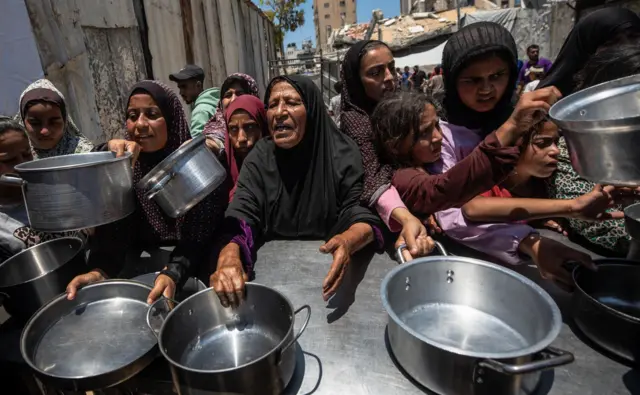 نازحون فلسطينيون يحملون أواني معدنية أثناء تجمعهم للحصول على وجبات ساخنة من مطبخ خيري في شمال مدينة غزة، 10 يونيو/حزيران 2026.