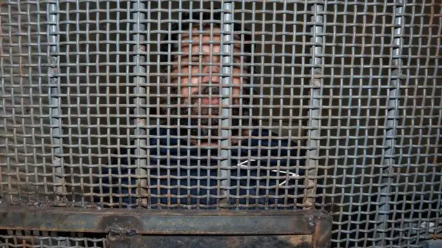 Alias Fito dey behind bars of a prison door for La Roca prison