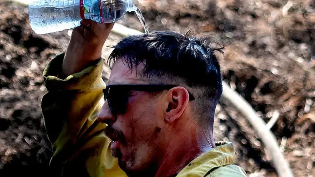 જૂન મહિનાથી પશ્ચિમ અમેરિકાના ભાગોમાં ગરમીનો પ્રકોપ જોવા મળી રહ્યો છે. સૅન બર્નાડિનોમાં લાગેલી આગને ઓલવવાના પ્રયત્ન કરતાં અગ્નિશમન વિભાગના કર્મીને પાણીથી રાહત મેળવવાનો પ્રયત્ન કરતાં જોઈ શકાય છે