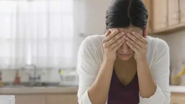 Una mujer se toma la cabeza con las manos.