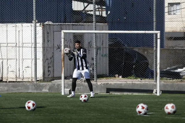 Un joven arquero para un balón durante la práctica en el campo a punto de ser demolido