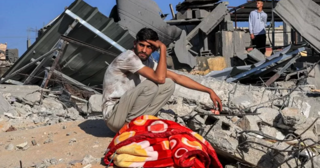 Un jeune Palestinien est assis près des décombres d'un bâtiment après une frappe aérienne israélienne à Rafah, dans le sud de la bande de Gaza, le 13 octobre 2023.