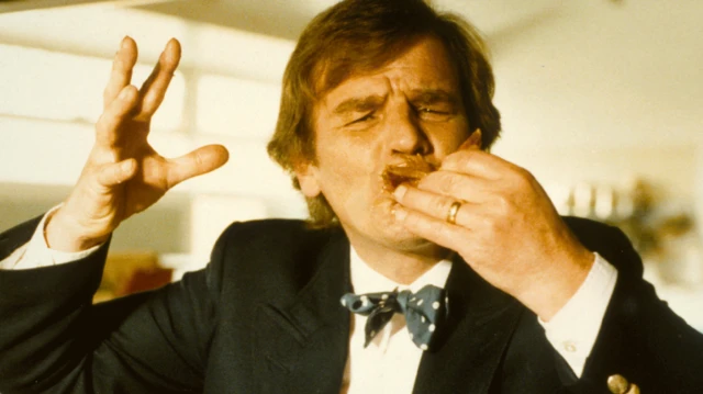 基斯·弗洛伊德穿着西装及领结，正在进食。