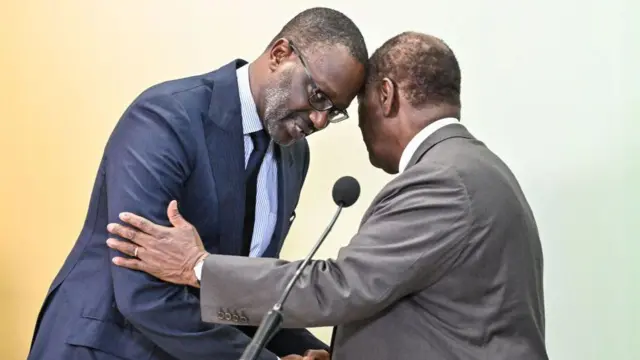 Le président ivoirien Alassane Ouattara (à droite) et le président du Parti démocratique de Côte d'Ivoire (PDCI) Tidjane Thiam (à droite) se serrent la main lors d'une conférence de presse à l'issue d'une réunion au palais présidentiel d'Abidjan, le 11 mars 2024.