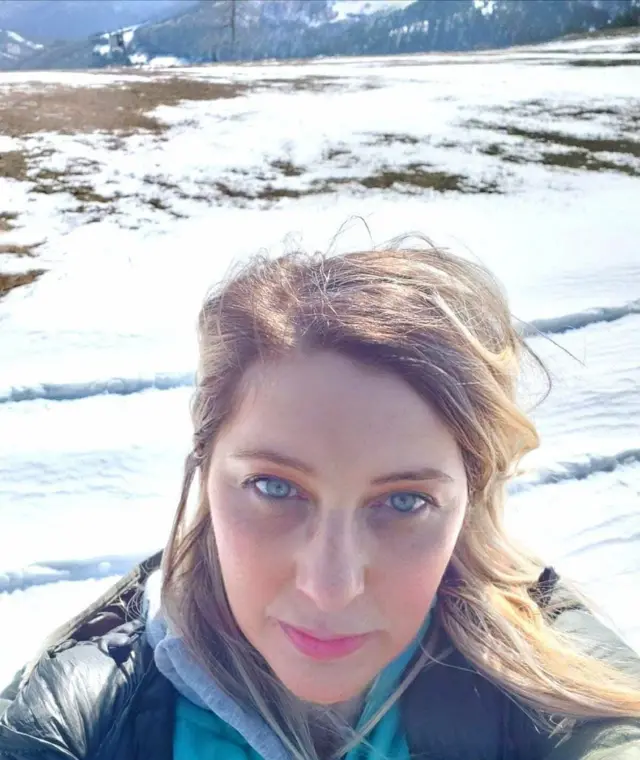 Nikolina Crnogorac fotografiše samu sebe, iza nje se vidi sneg, nosi crnu jaknu ima smeđu kosu