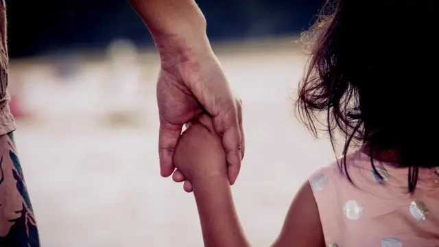 मां का हाथ पकड़े बच्ची