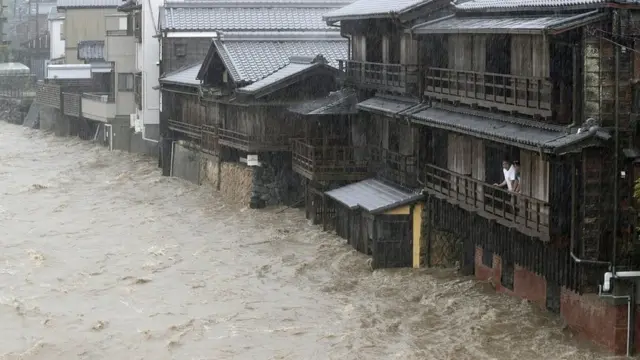 Un hombre mira por el balcón la inundación en Ise.
