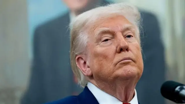 Trump perto de microfone com olhar sério