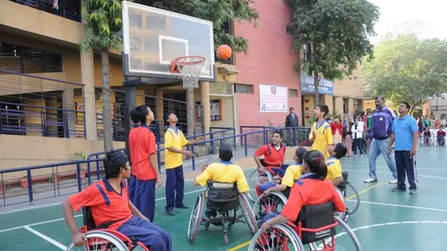 बच्चे व्हीलचेयर पर बास्केटबॉल खेलते हुए