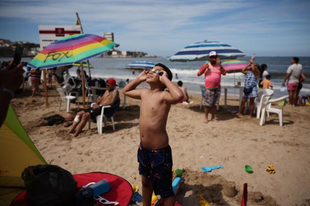 Un niño con lentes especiales para ver el eclipse en una playa en Mazatlán, México.