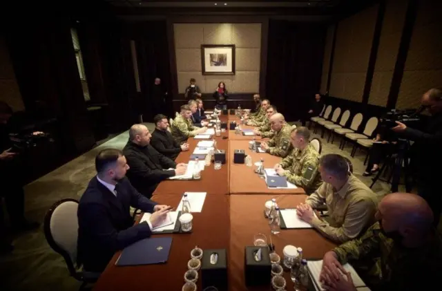Зеленський і люди у формі сидять за довгим столом