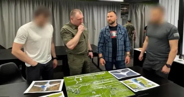Чотири чоловіки дивляться на карту на столі