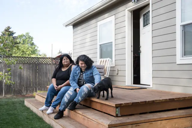Sherry Mesa (E) e sua sobrinha, Sobeyda (D), sentadas em frente à microcasa em que vivem desde julho no quintal de Martha Chambers, nos EUA. Elas antes eram sem-teto