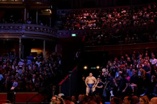 ロイヤル・アルバート・ホールで、大の里がまわし姿で通路に立っている。周囲では満員の観客が前方を見ている