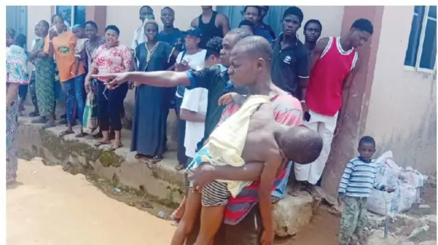 Paul Onyeama, ọkọ to gba Faith tọ, gbe ọmọ naa dani, awọn eeyan pejọ.