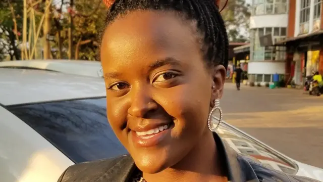 A close-up of Nelly Naisula Sironka smiling with one hooped bejewelled earring visible