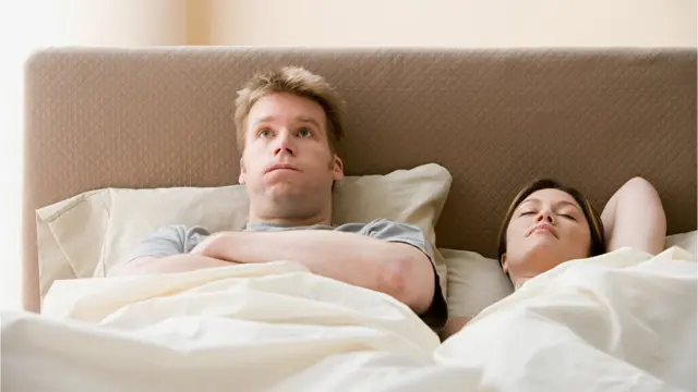 Un hombre acostado con cara de preocupación.