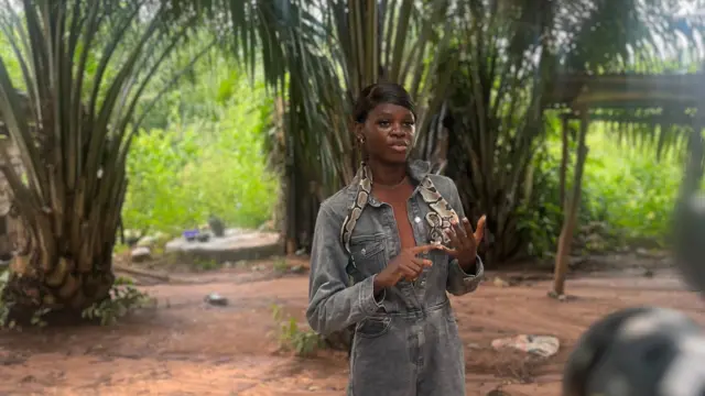 Woman put snake for neck, she raise her hand wit palm tree for back
