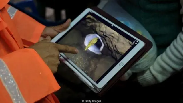 बचाव अभियान की तस्वीरें दिखाता पुलिसकर्मी