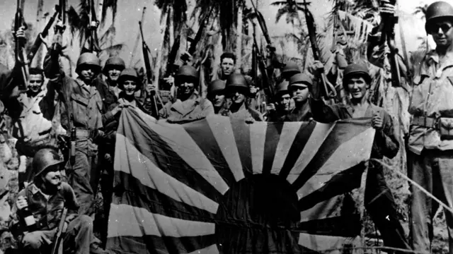 ทหารอเมริกาแสดงอาการภูมิใจที่ปลดธงรบของญี่ปุ่นลงจากยอดเสาได้