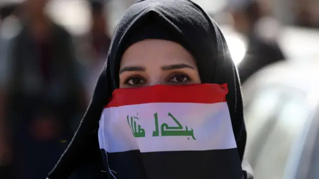 امرأة ترتدي العلم العراقي كمامة في زمن الوباء