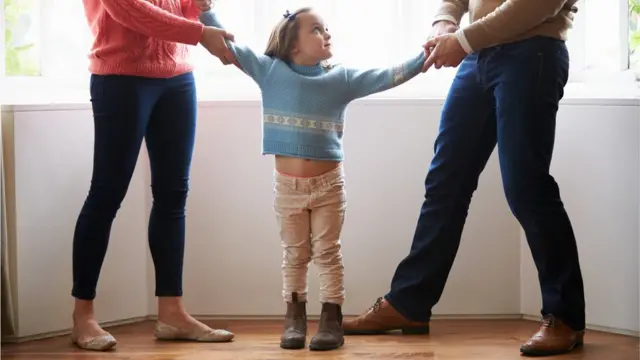 Casal puxando menina pelos braços